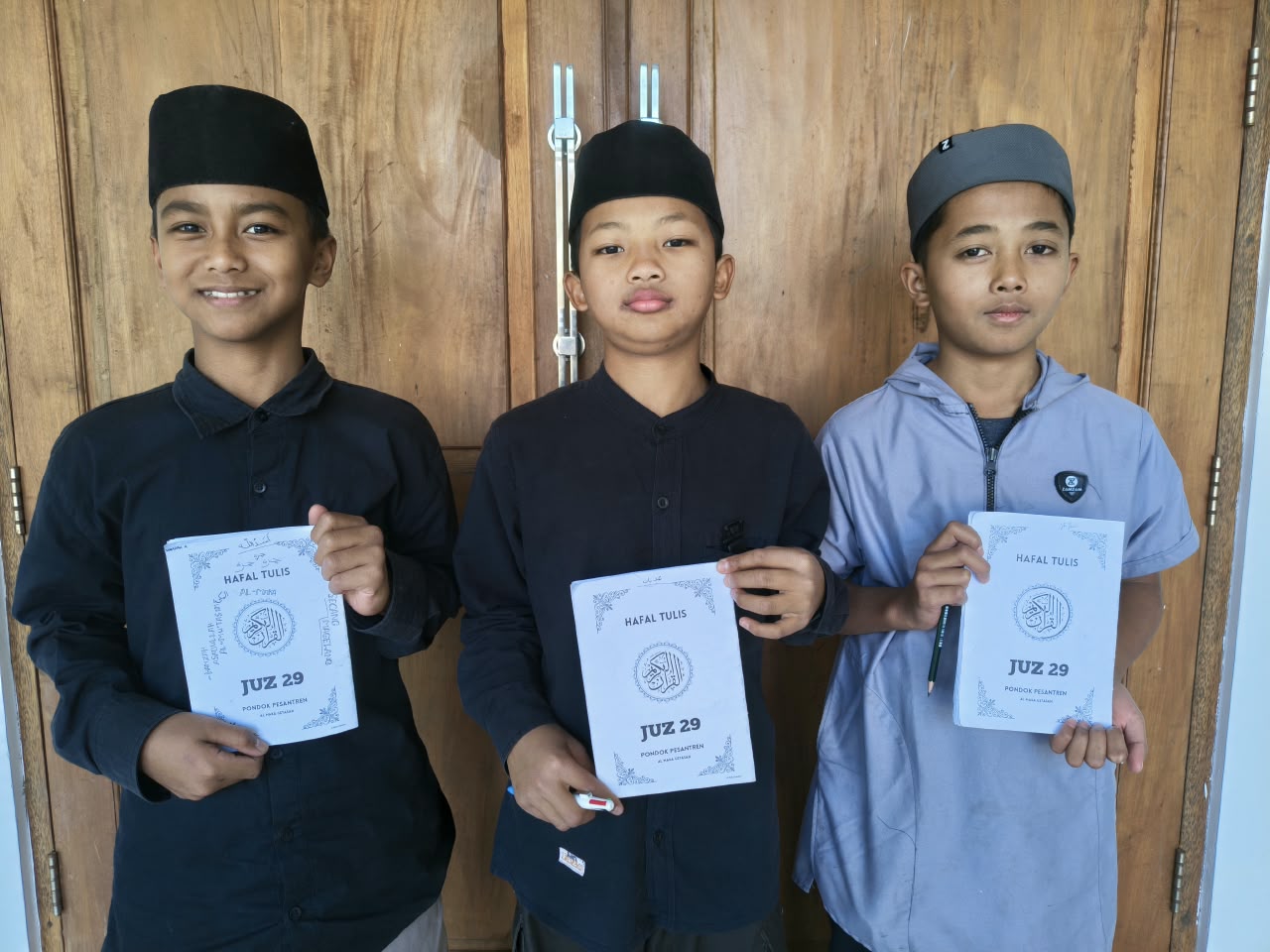 Tiga santri Al Maka memegang buku Hafal Tulis Juz 29