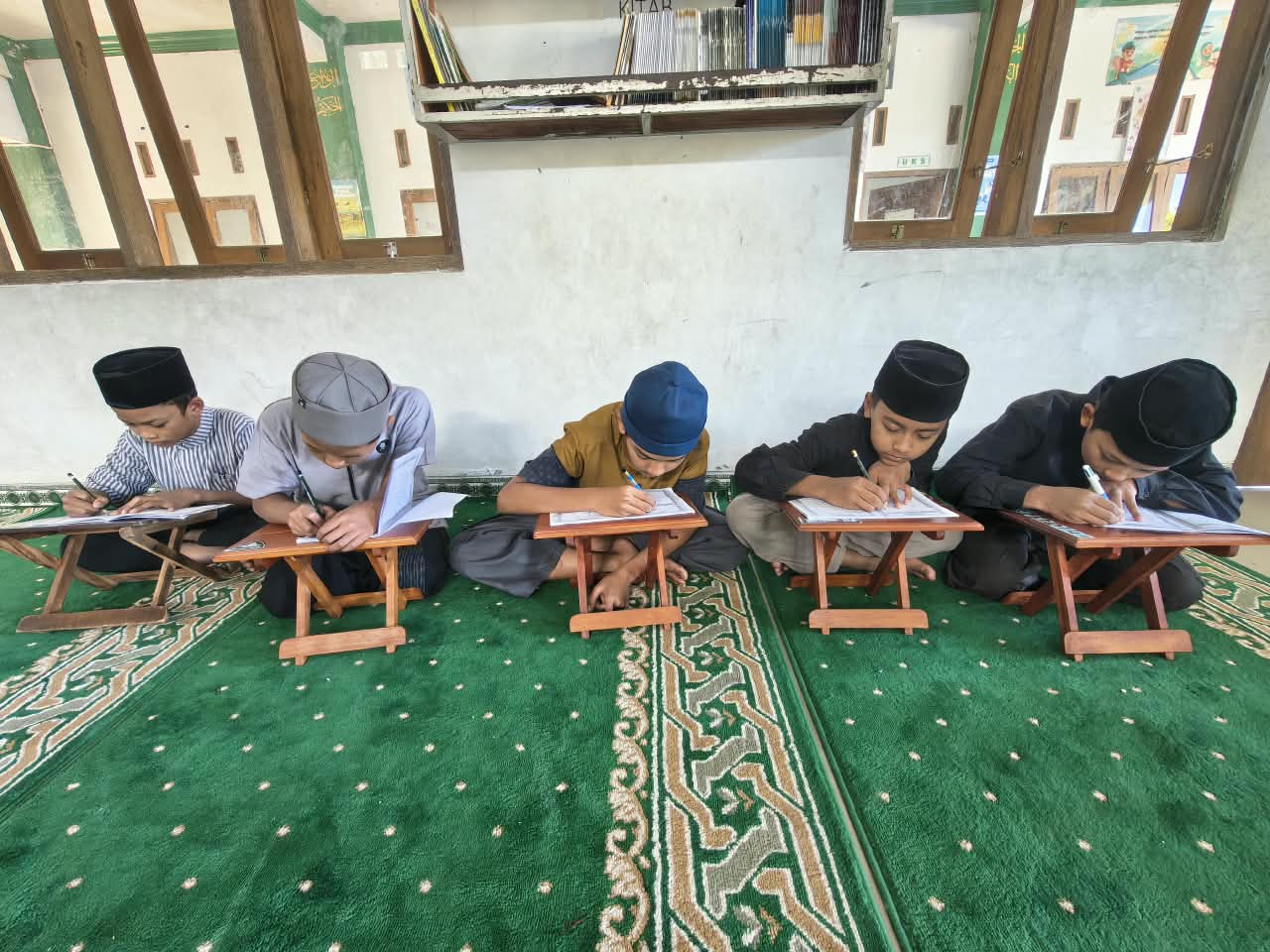 Santri menulis hafalan di atas rehal di masjid pondok