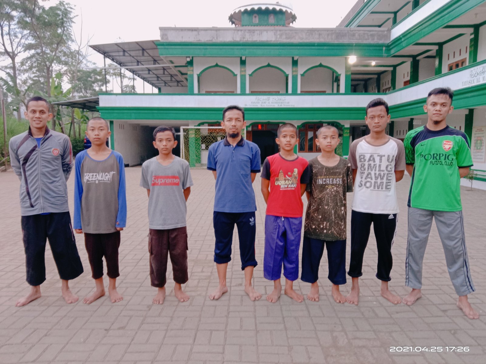 Ustadz dan santri berdiri berjajar di halaman pondok seusai bermain bola