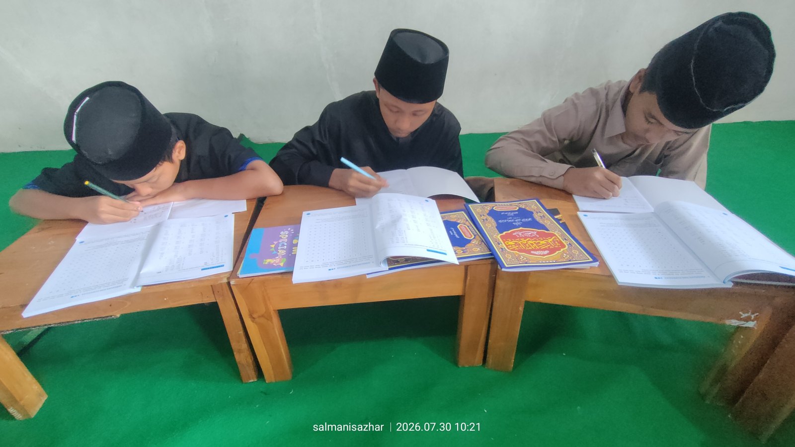 Tiga santri mengerjakan soal berhitung di meja masing-masing