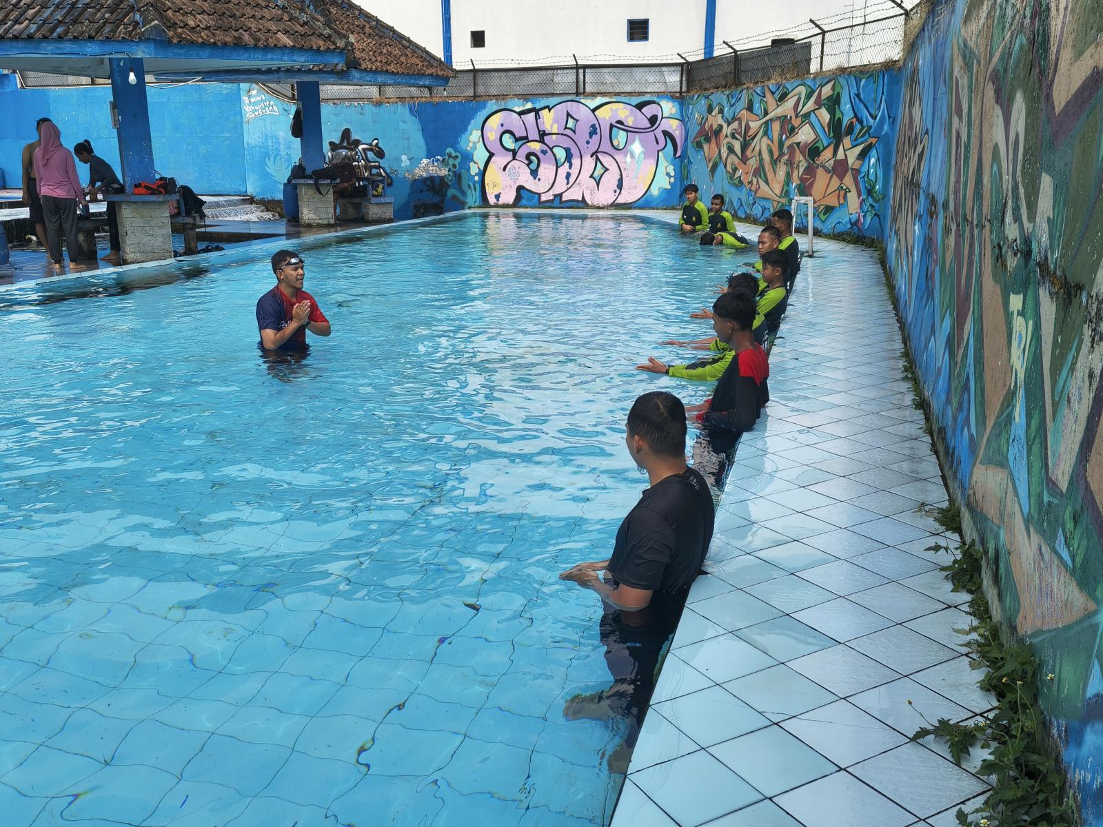 Santri di sepanjang dinding kolam menirukan contoh gerakan tangan dari Ustadz Salman